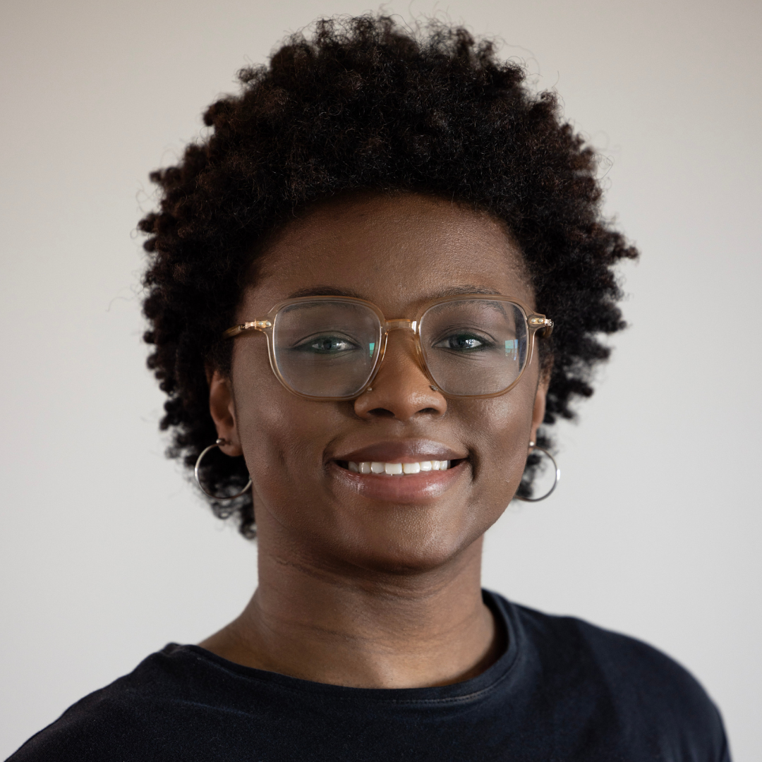 A woman wearing glasses and earrings is smiling for the camera.