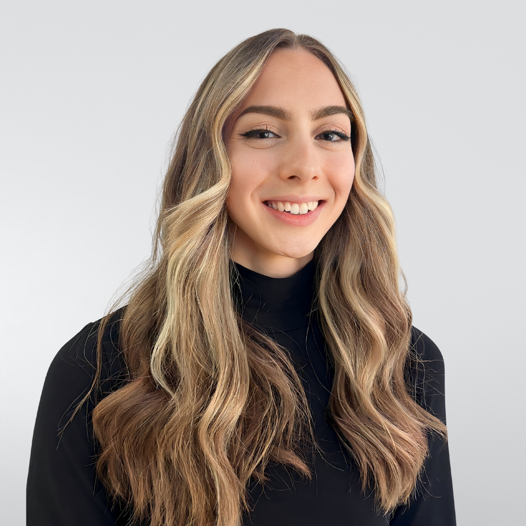 A woman with long hair is wearing a black turtleneck and smiling.