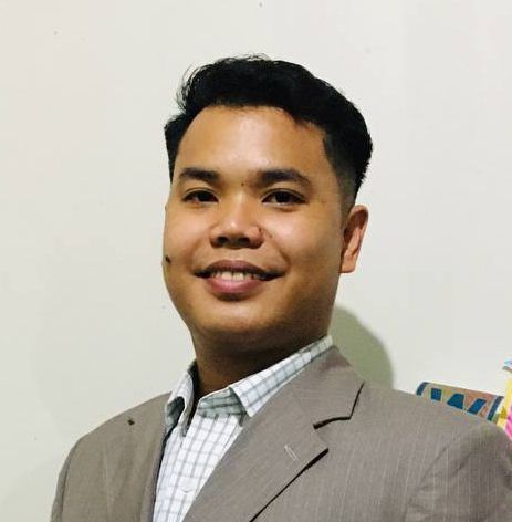 A man in a suit and plaid shirt is smiling for the camera.