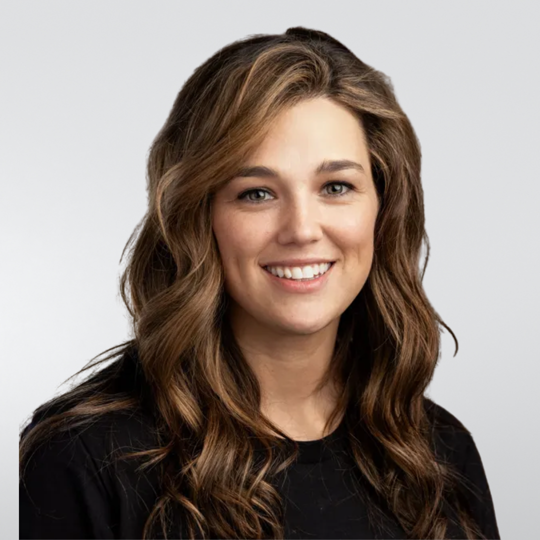 A woman with long blonde hair is smiling and wearing a black shirt.