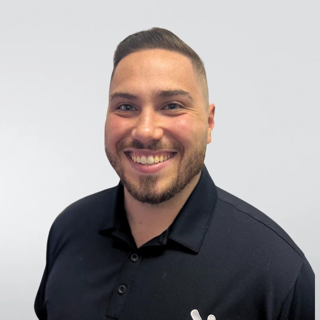 A man with a beard is wearing a black shirt and smiling.