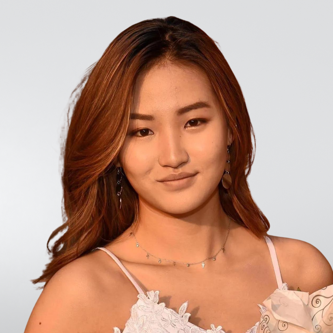 A woman with long brown hair is wearing a white dress and earrings.