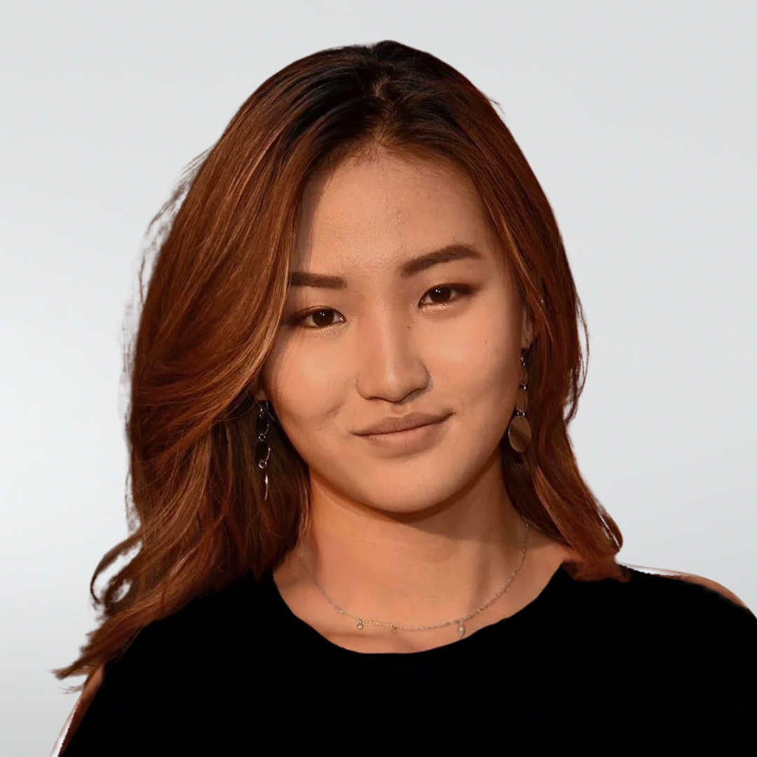 A woman with long brown hair is wearing a white dress and earrings.