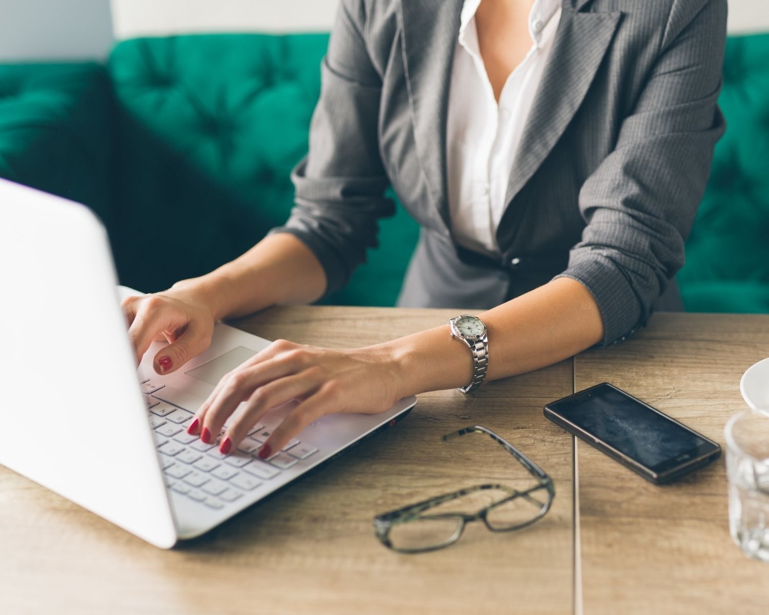 woman sitting on couch typing on laptop