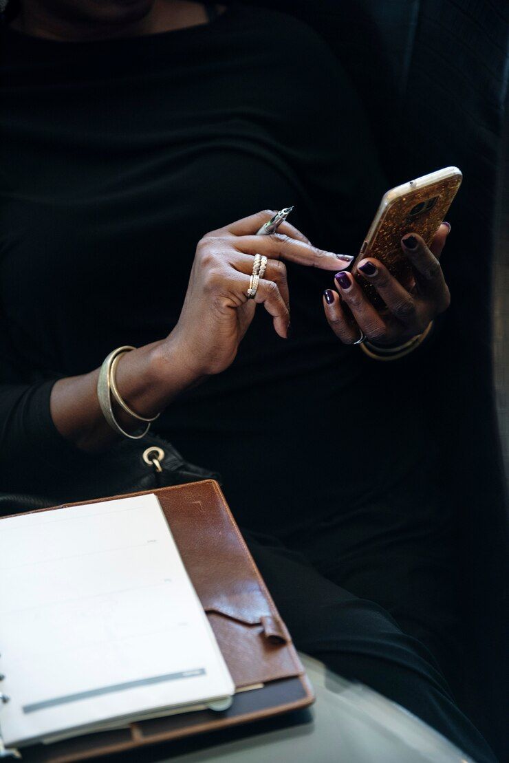 A woman is sitting at a table using a cell phone.