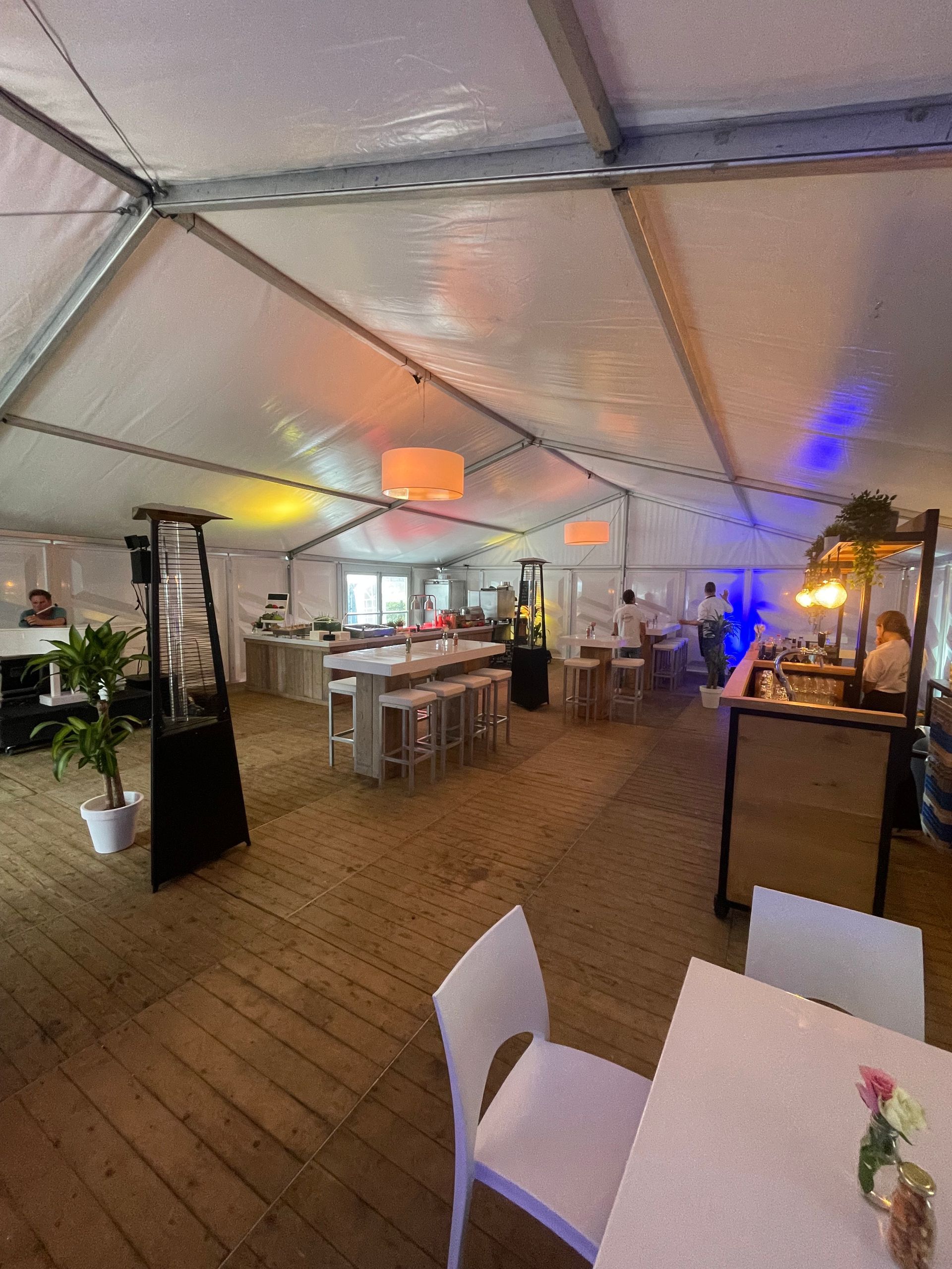 Een grote ruimte met tafels en stoelen onder een tent.