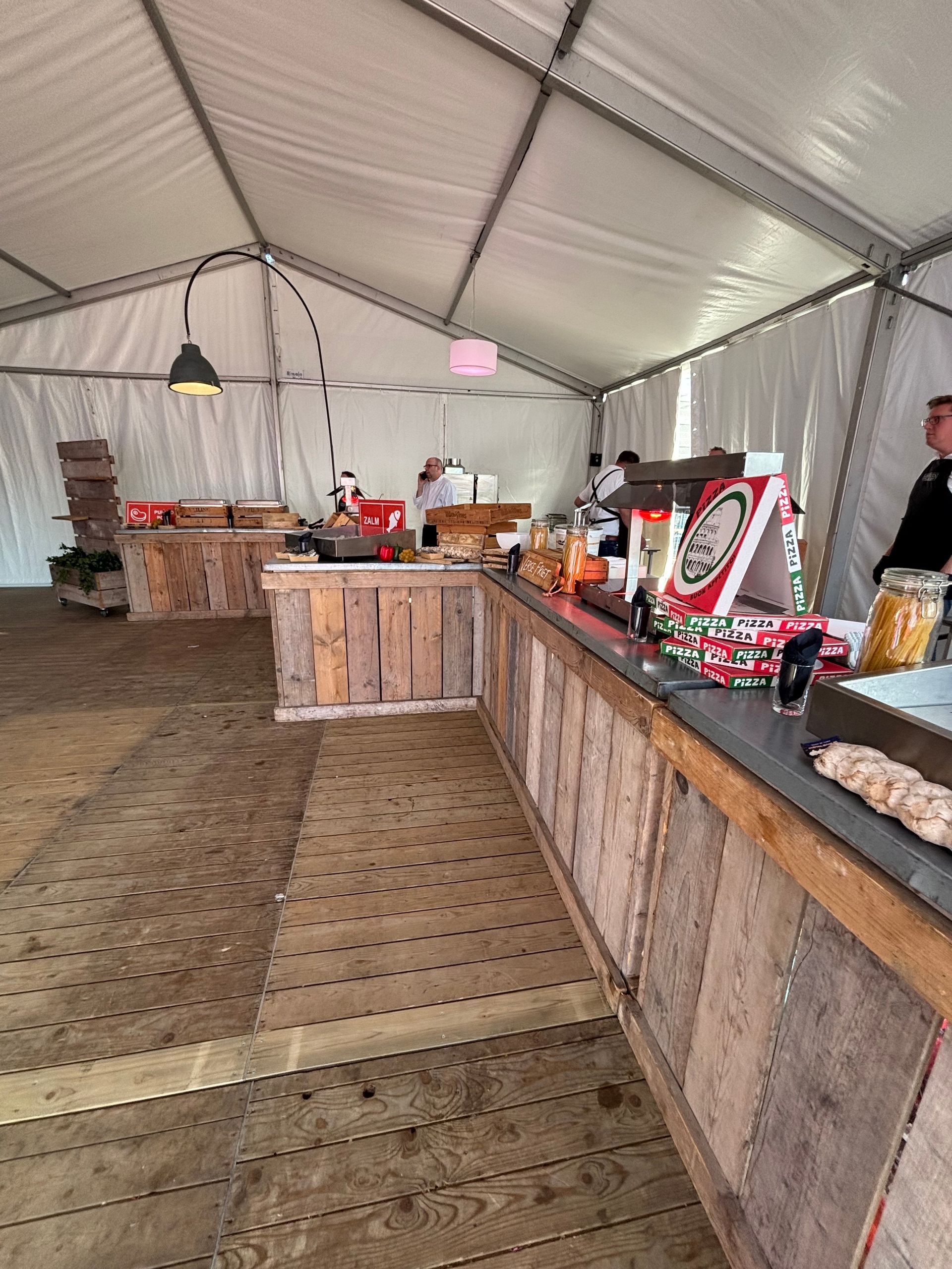 Een man staat achter een houten toonbank in een tent.
