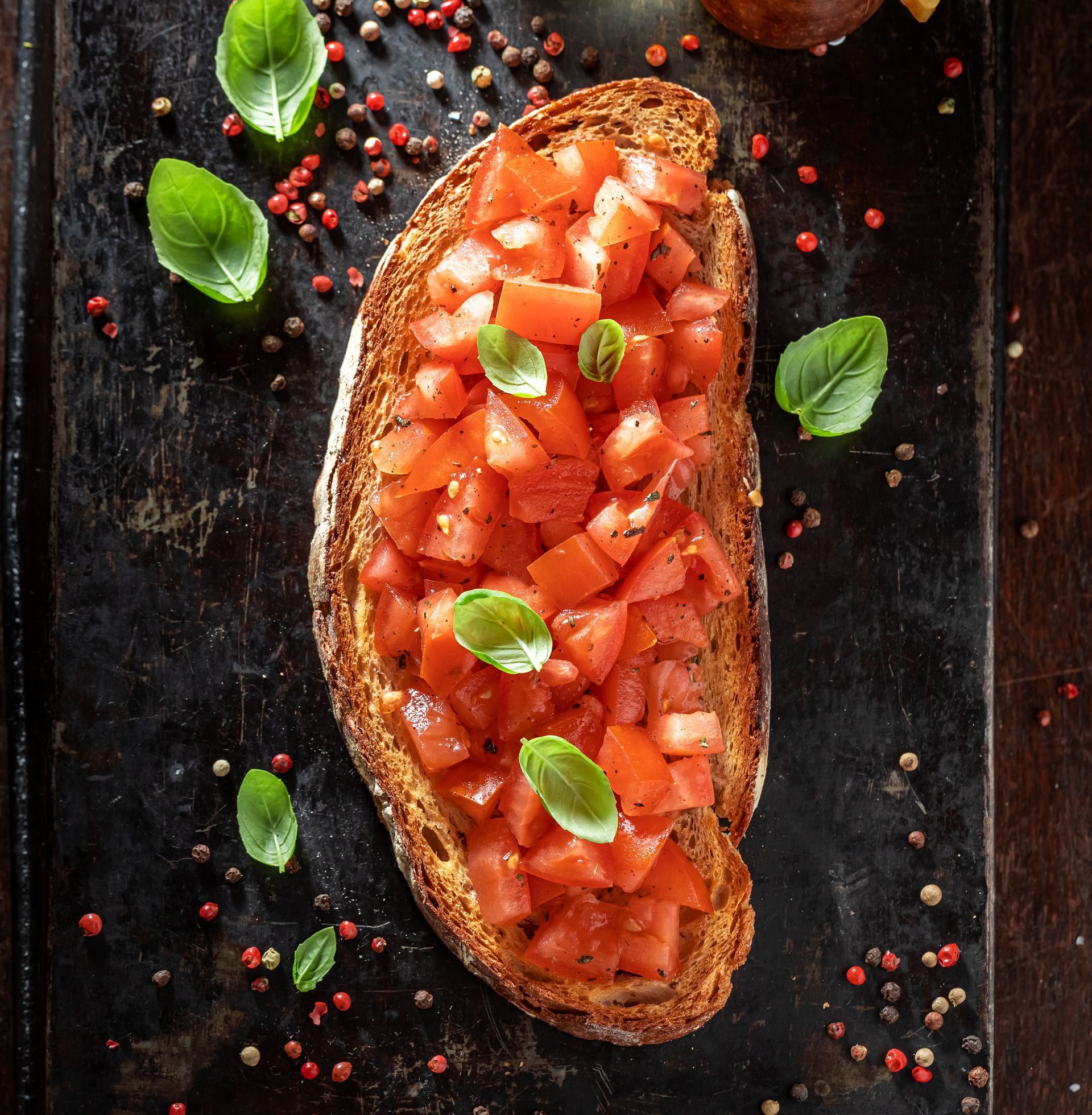 Een sneetje brood met tomaten en basilicum erop