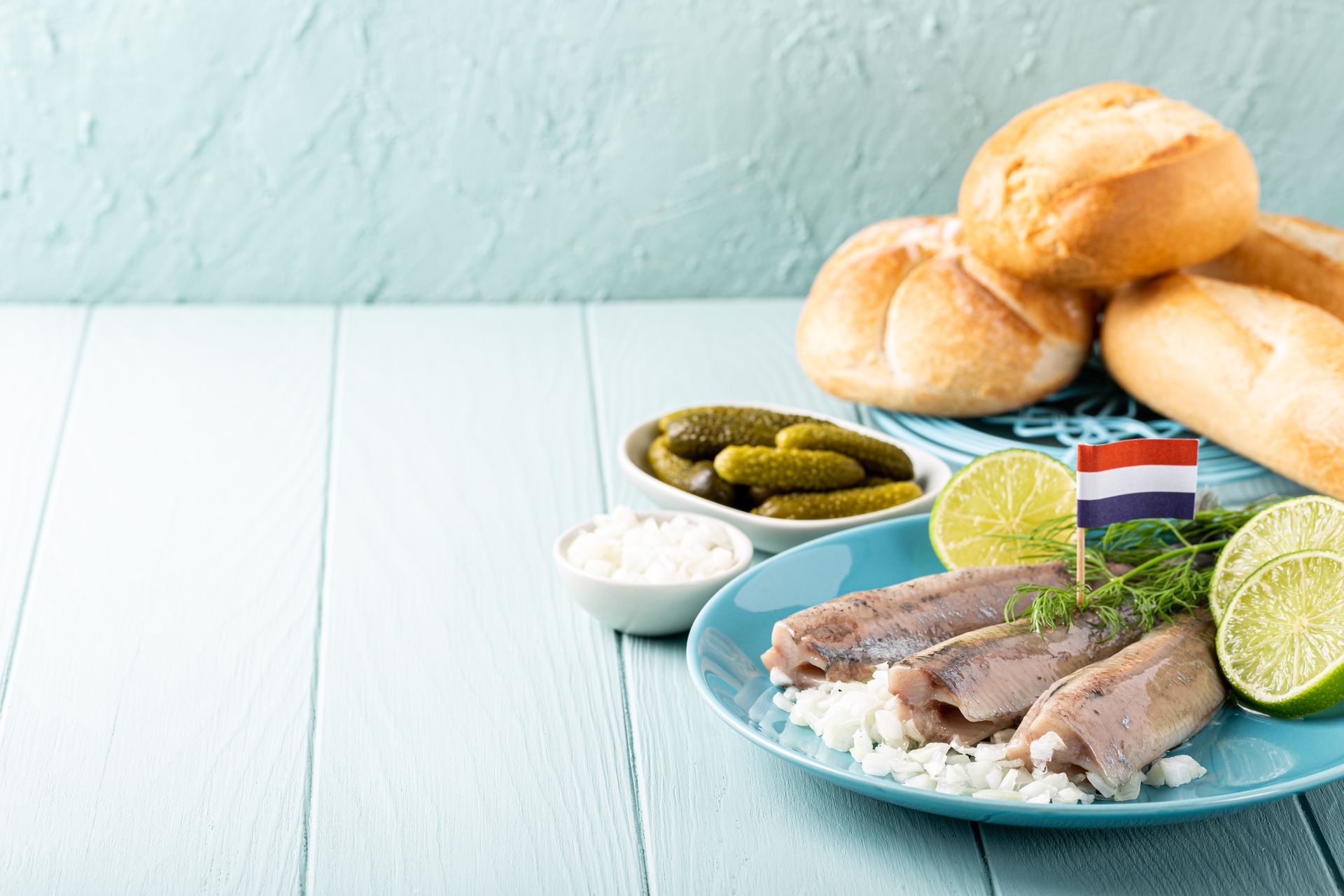 Een blauw bord met vis, rijst, augurken en limoenen op tafel.