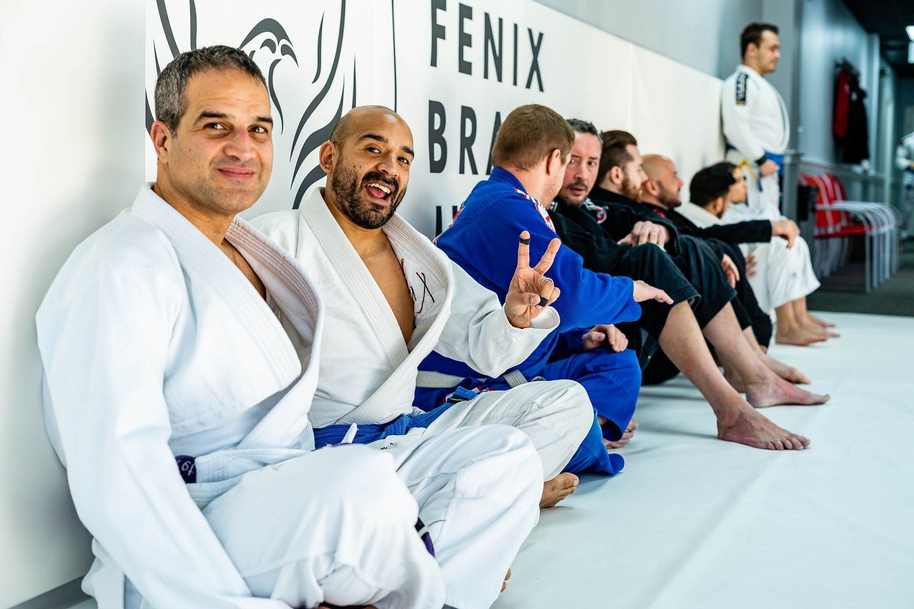 A group of men are sitting on a mat at Fenix Brazilian Jiu Jitsu gym