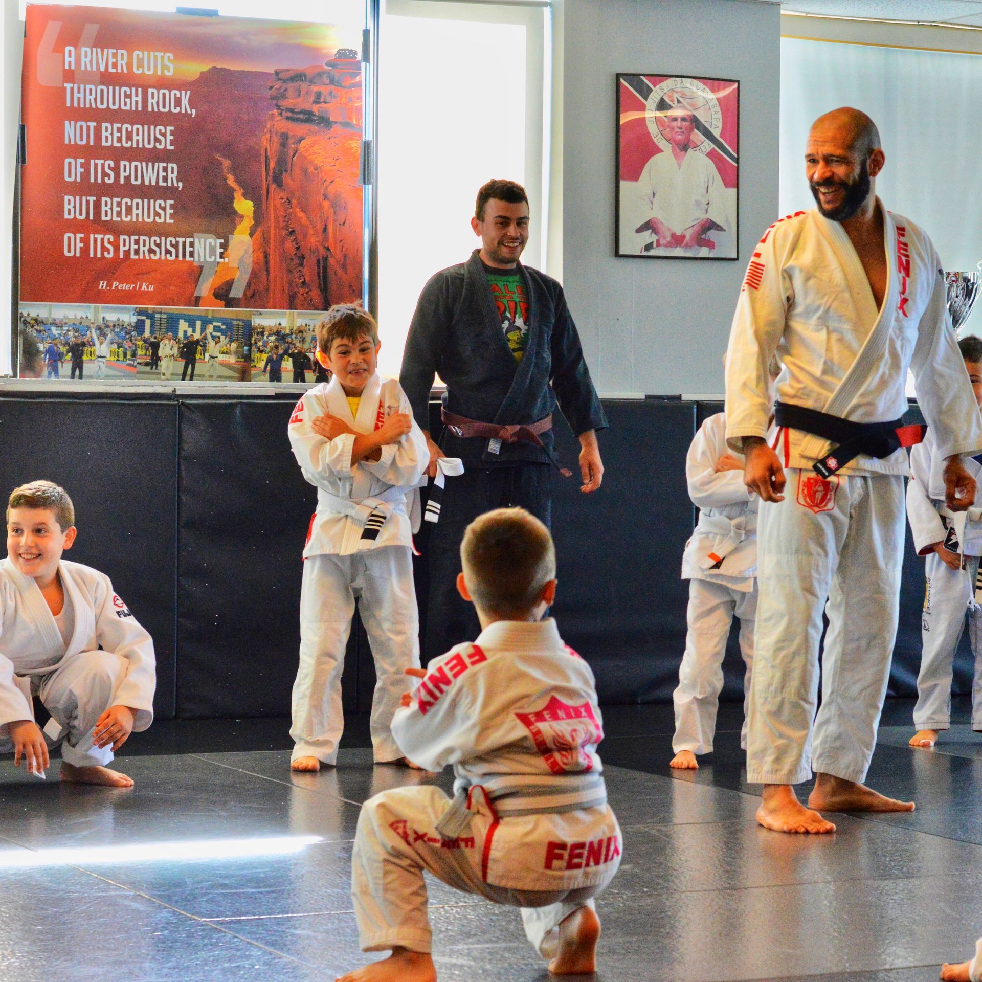 A group of kids are practicing martial arts in front of a poster that says power cuts through rocks