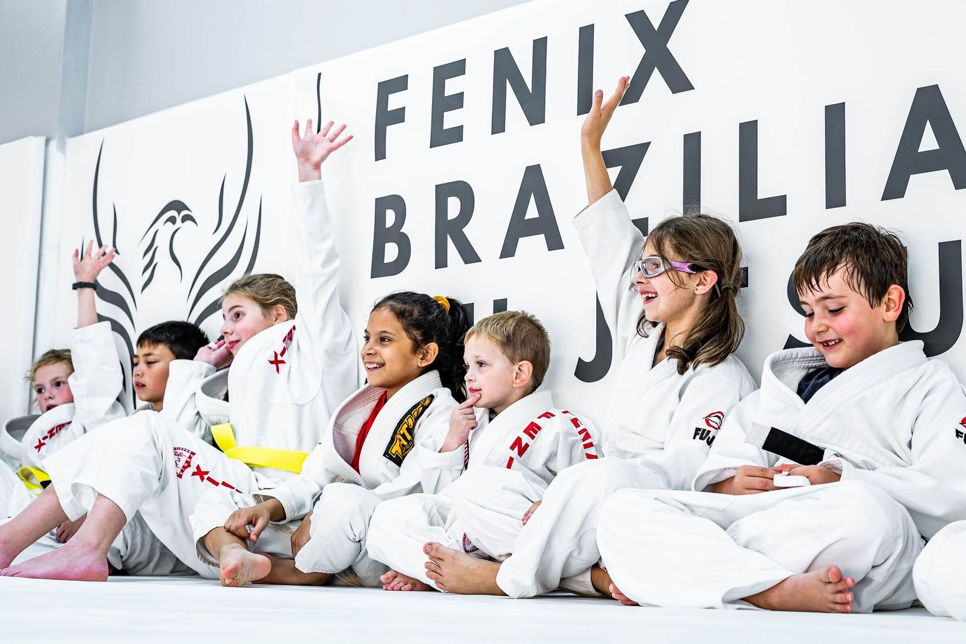 A group of children are sitting on the floor at Fenix Brazilian Jiu Jitsu