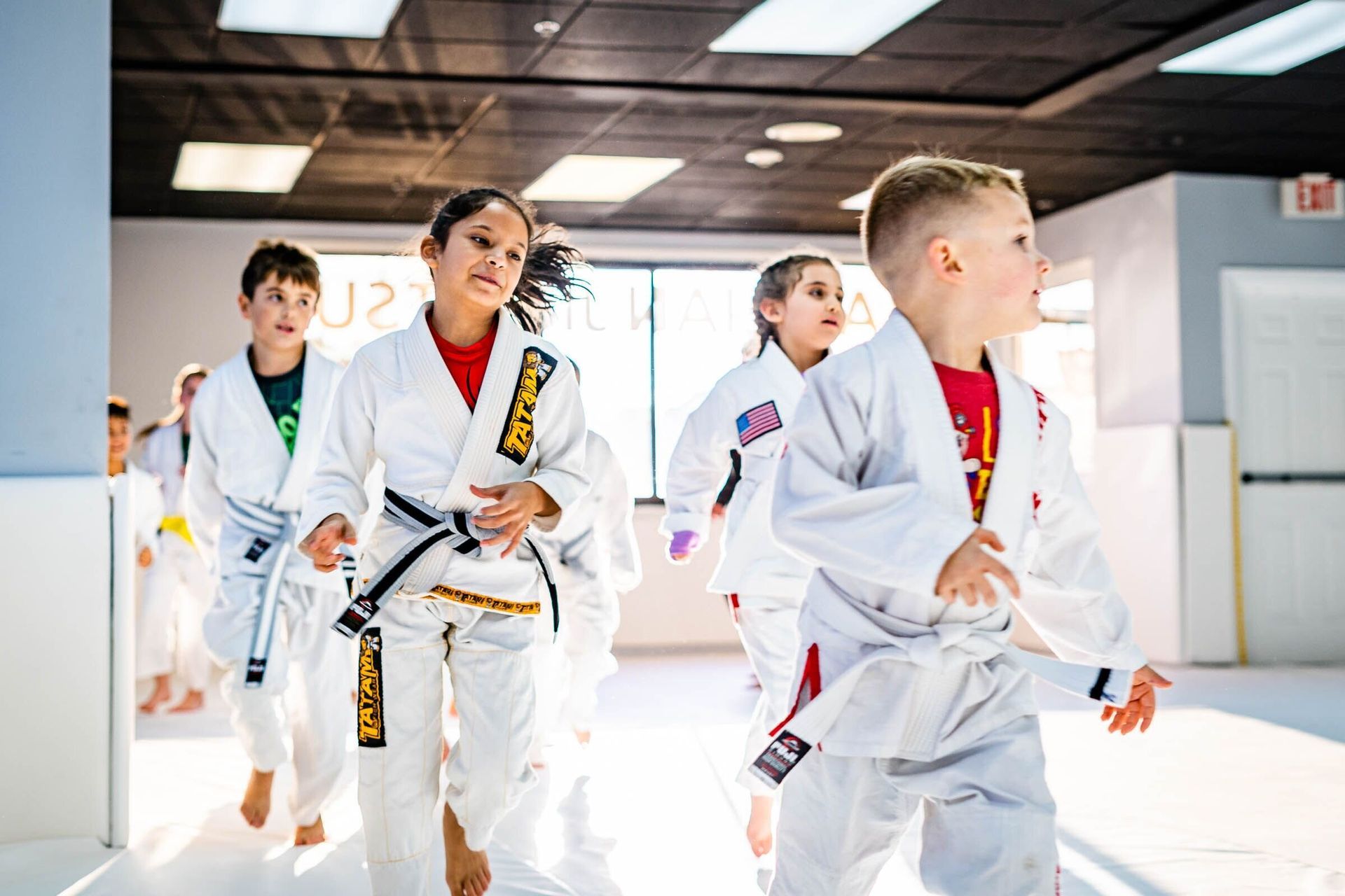 A group of children are practicing martial arts in a gym.