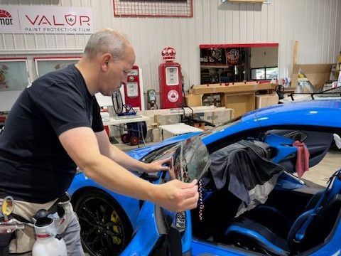 A man is working on a blue car in a garage.