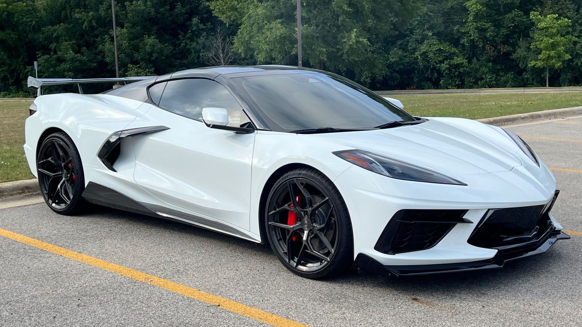 A red sports car is parked in a garage next to a white sports car.
