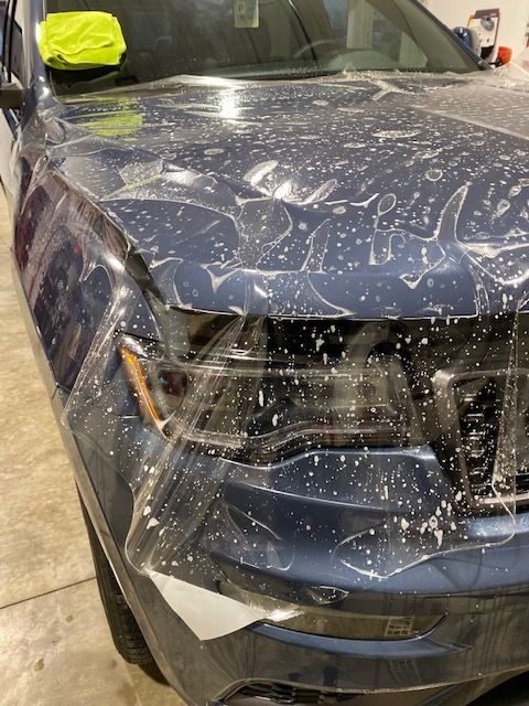 A blue car is wrapped in plastic and sitting in a garage.