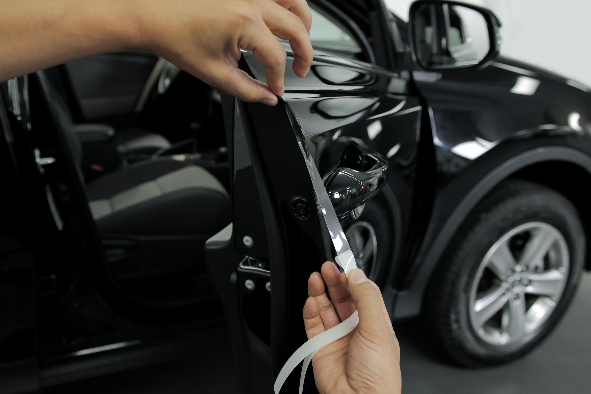 A person is holding a piece of tape in front of a car