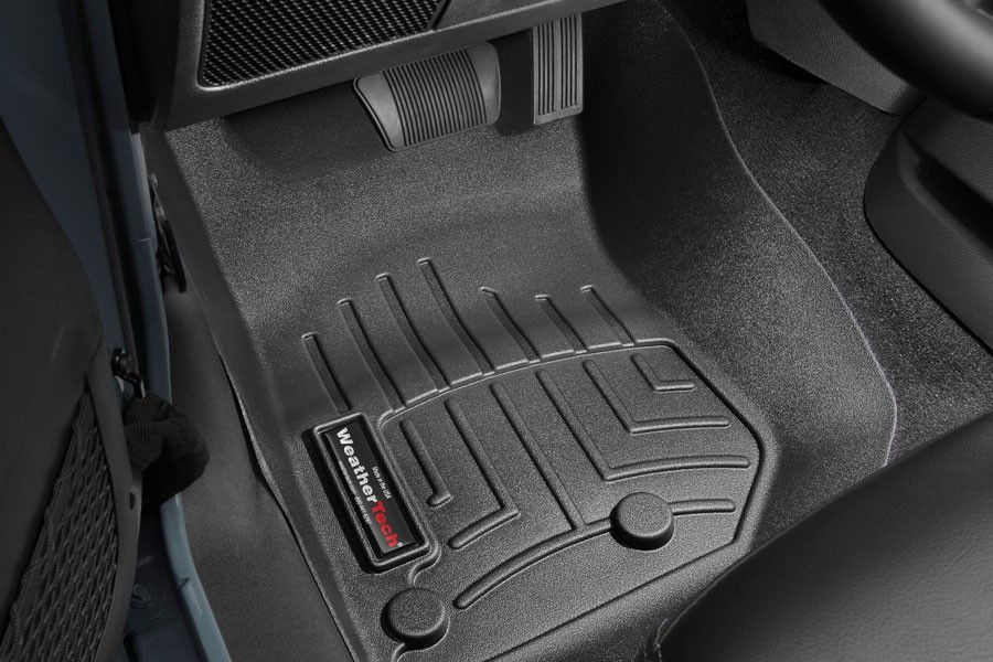 A black floor mat is on the floor of a car.