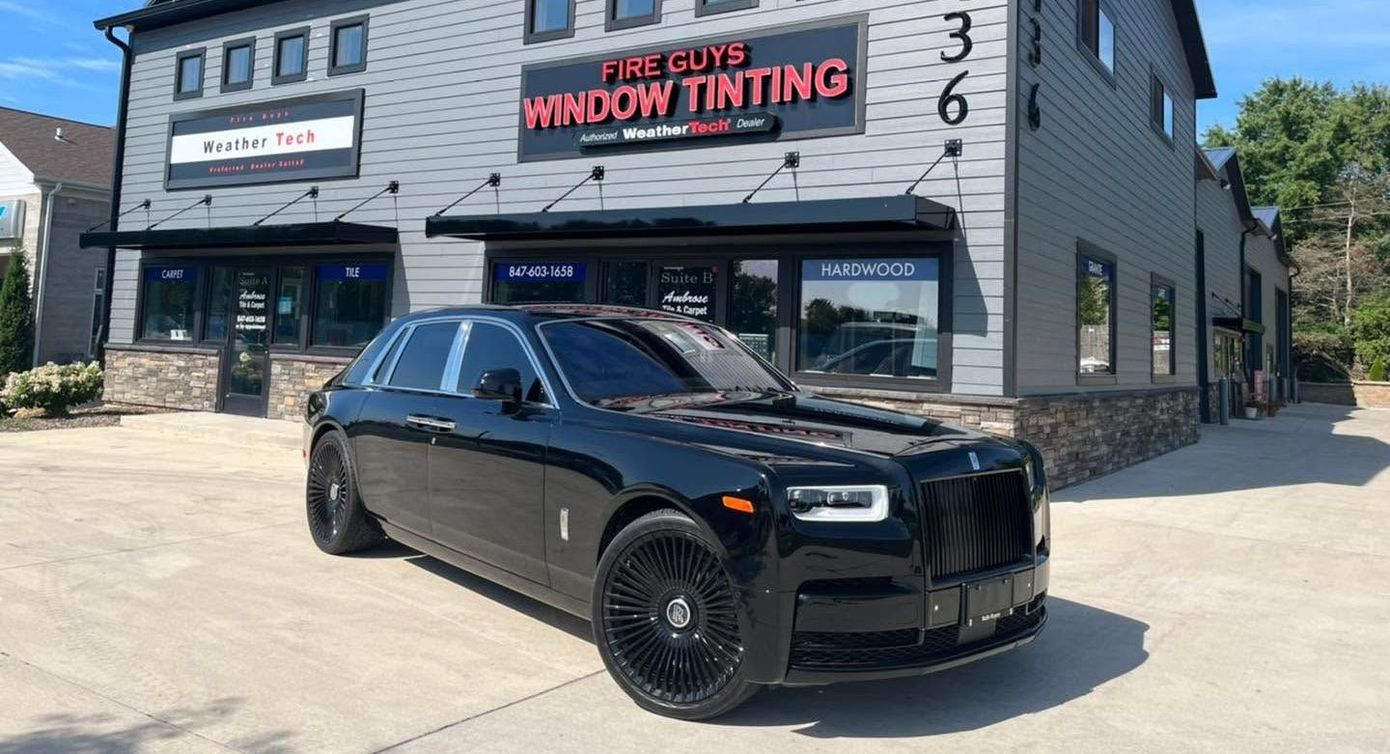 A black car is parked in front of a building.