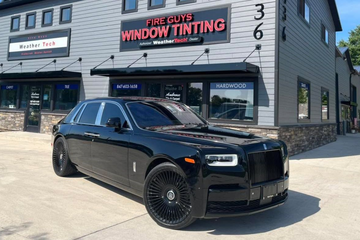 A black car is parked in front of a building.