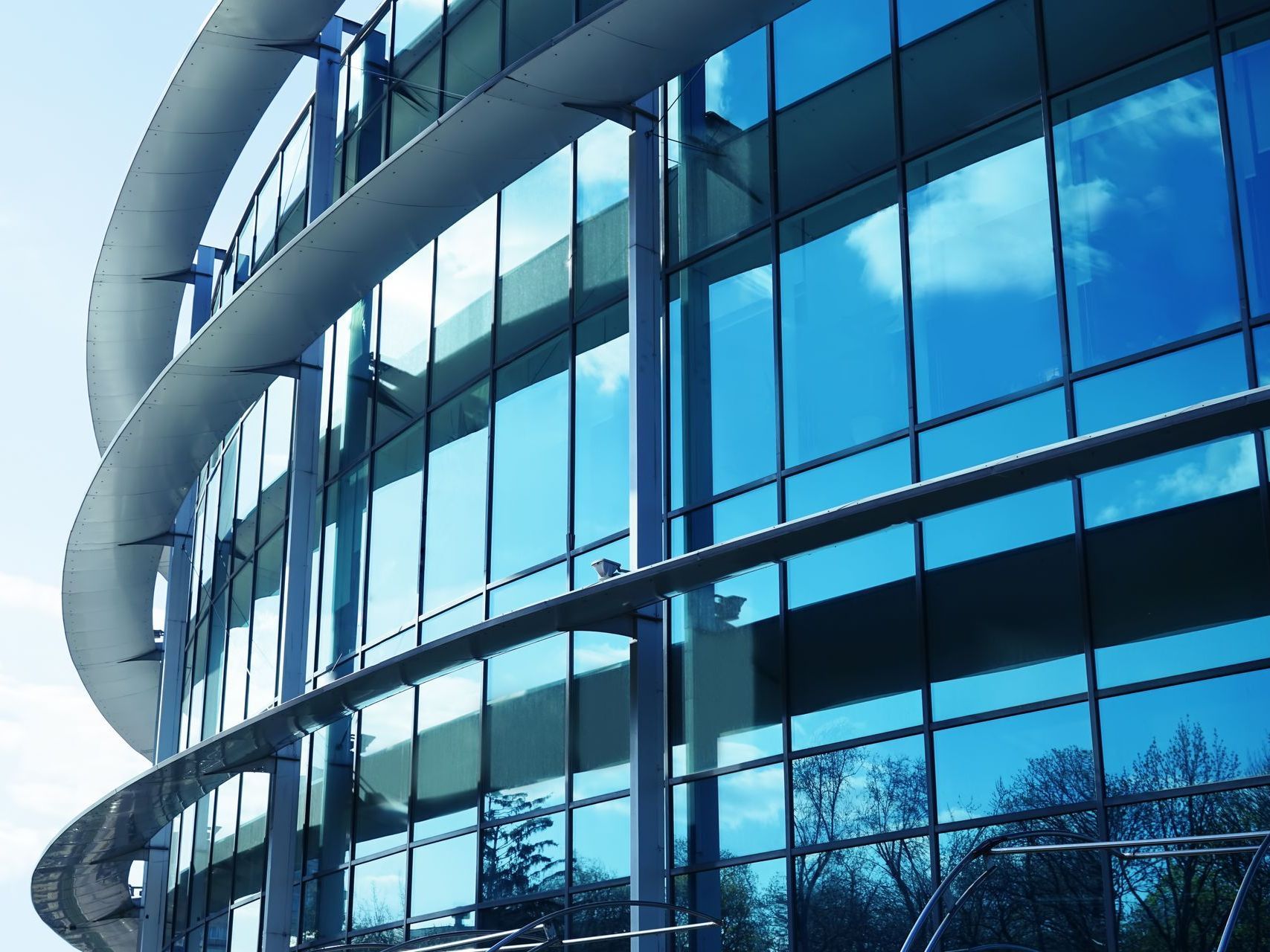 A large building with a lot of windows has a blue sky reflected in the windows