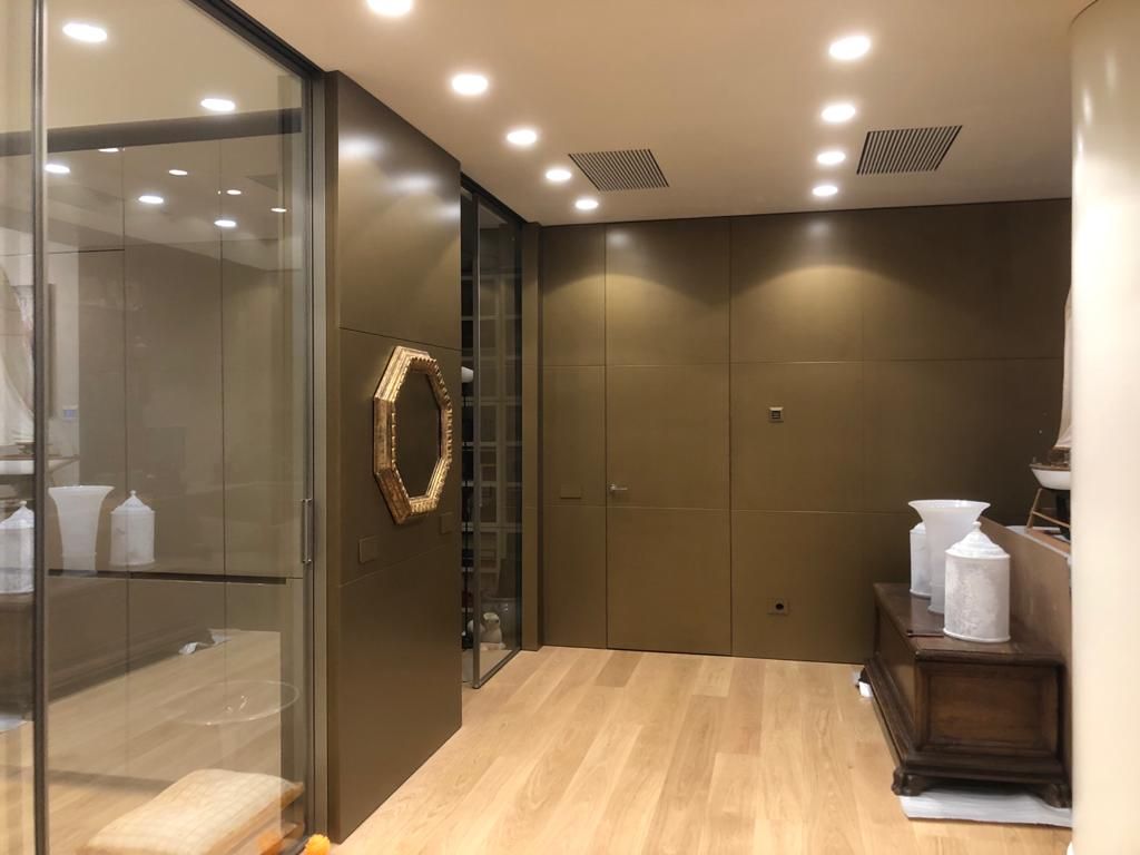 Un corridoio con pavimenti in legno e uno specchio sul muro.