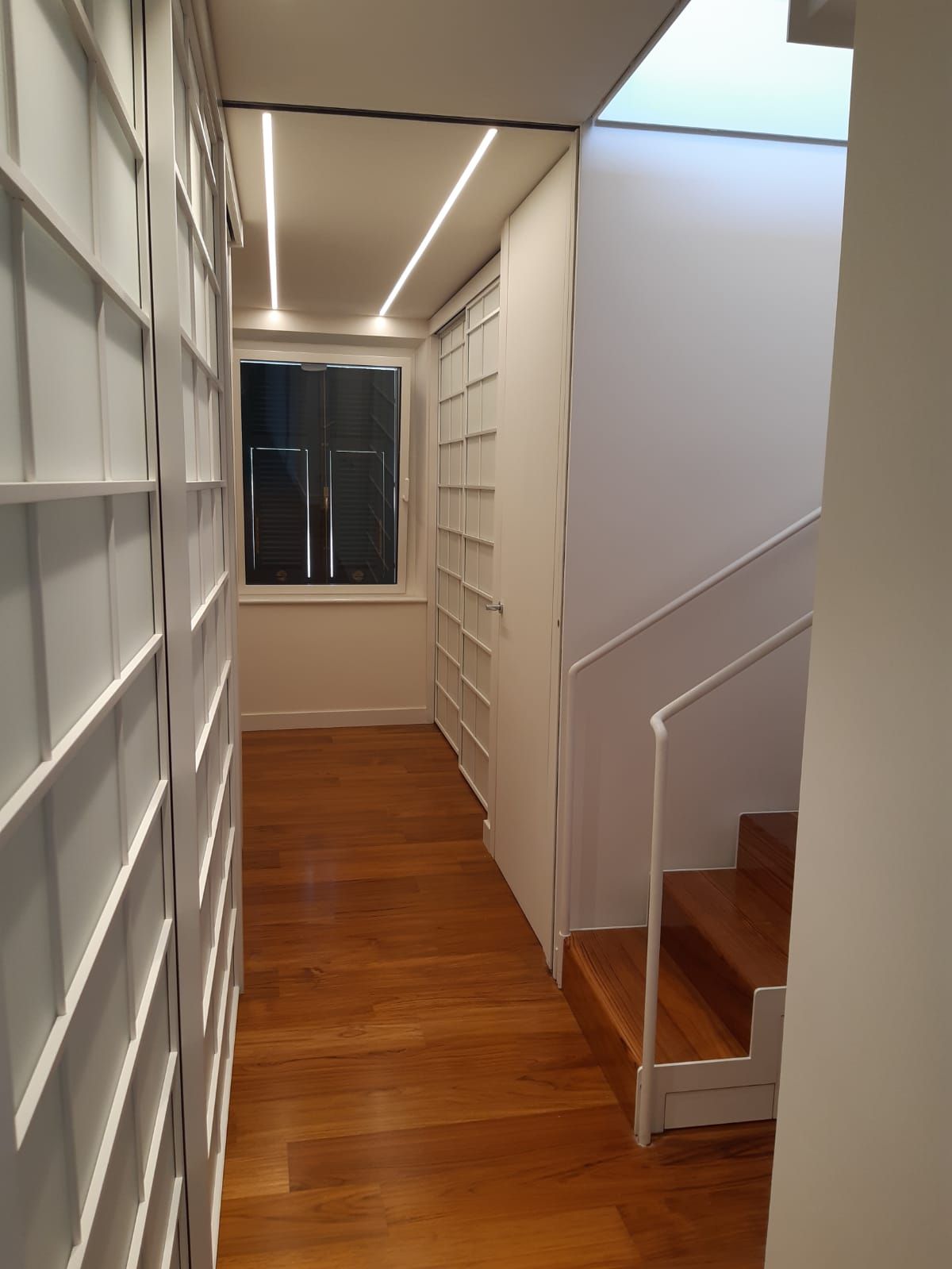 Un corridoio con pavimenti in legno e scale in una casa