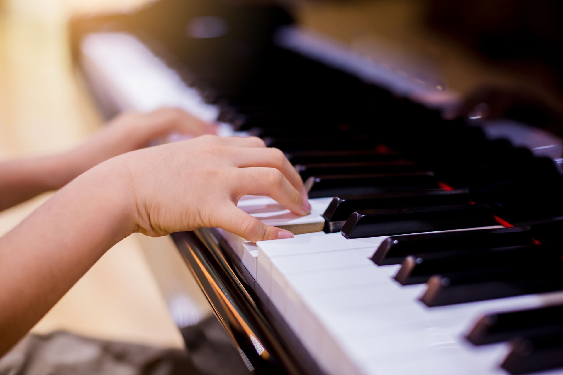 A person is playing a piano with their hands on the keys.