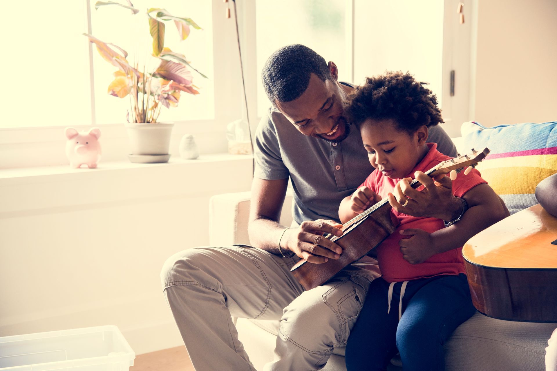 A man is teaching a little girl how to play a guitar.