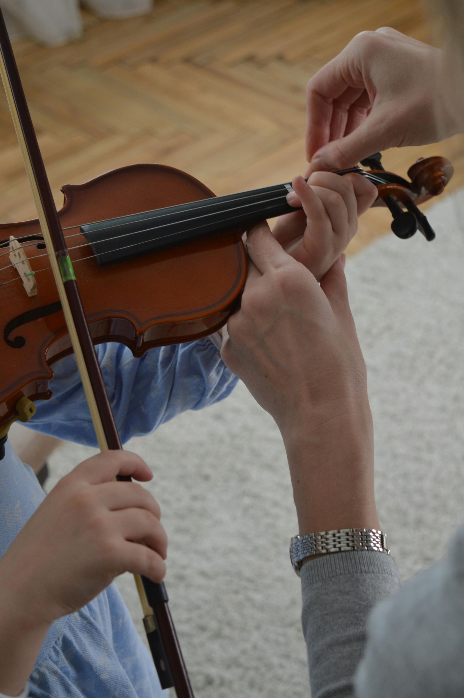 A woman is teaching a child how to play a violin.