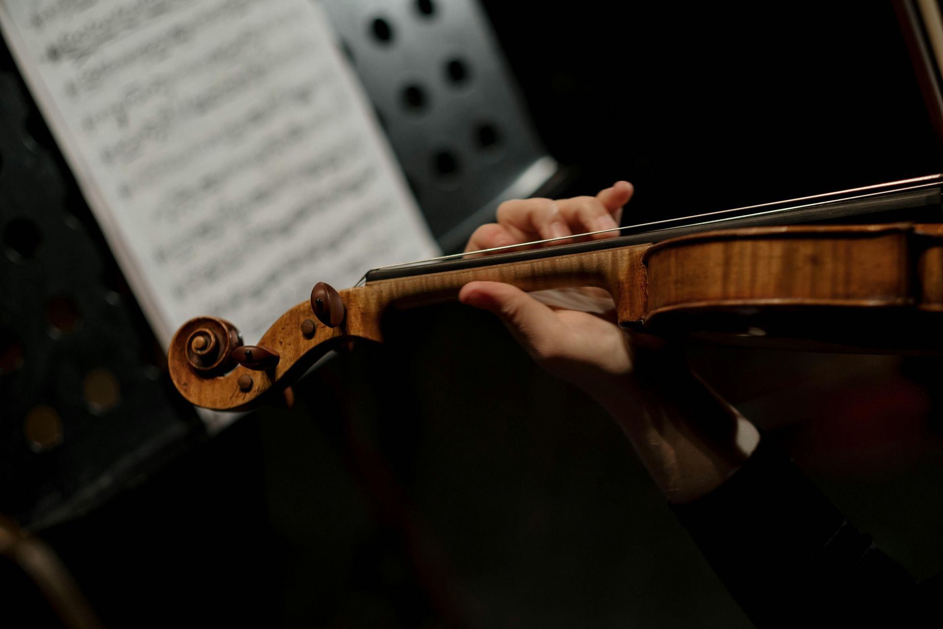 A person is playing a violin in front of sheet music.