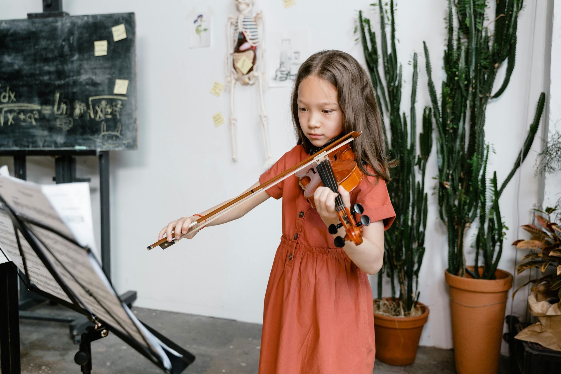 A young girl is playing a violin in a room.