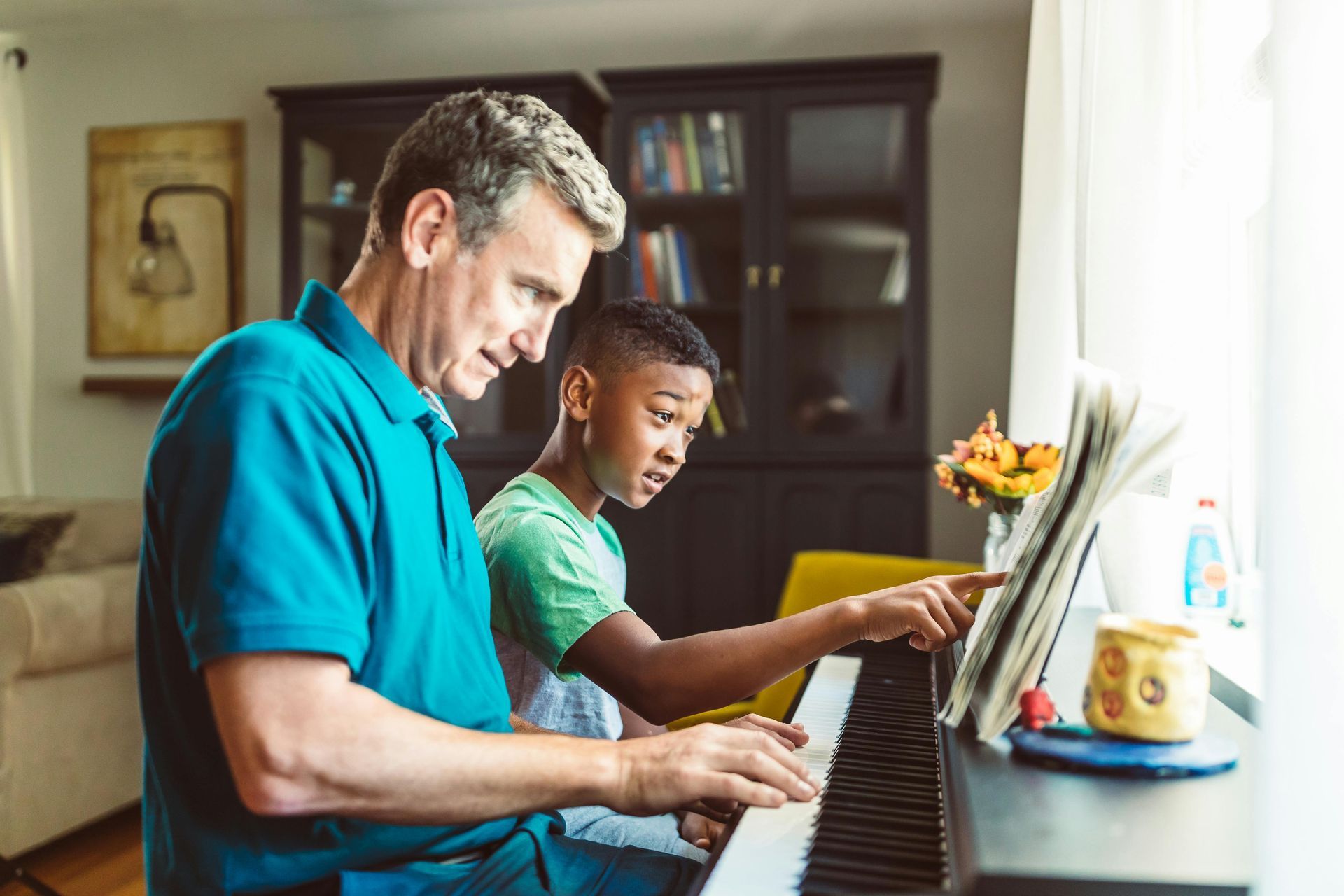 A man is teaching a young boy how to play the piano.