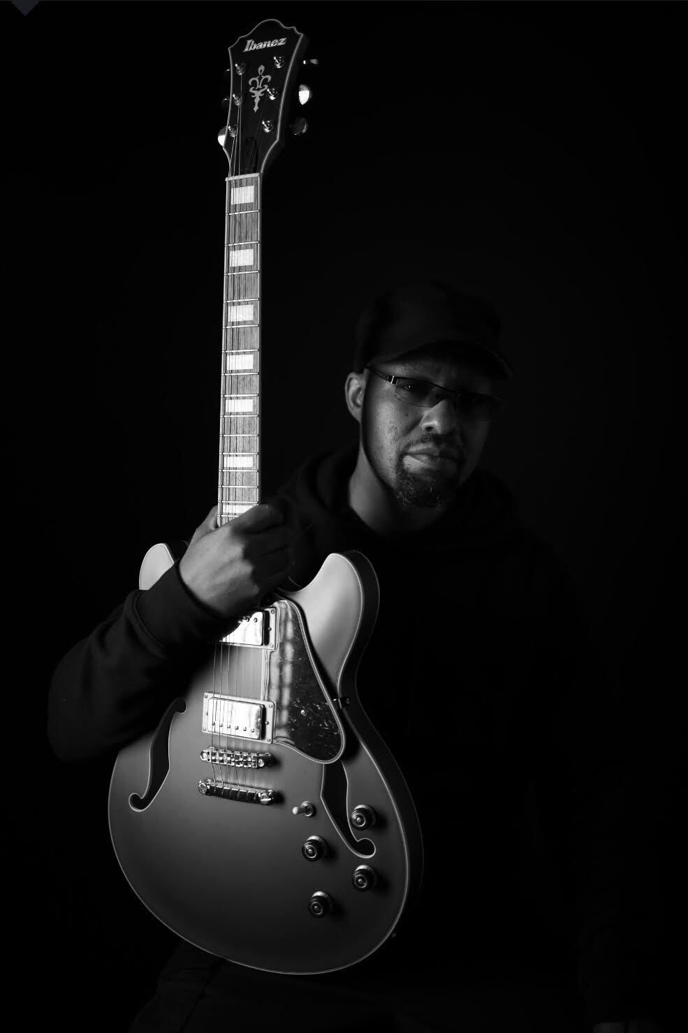 A man is holding a guitar in a black and white photo.