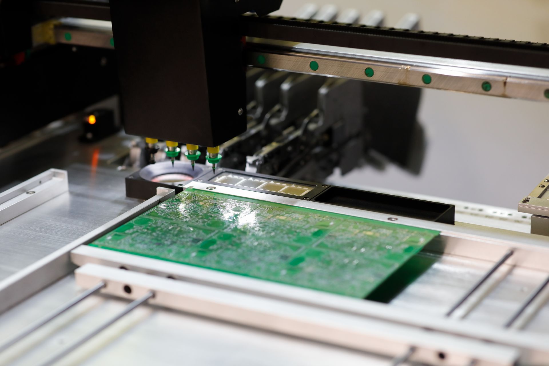Circuit board being assembled by a robotic arm in an electronics factory.