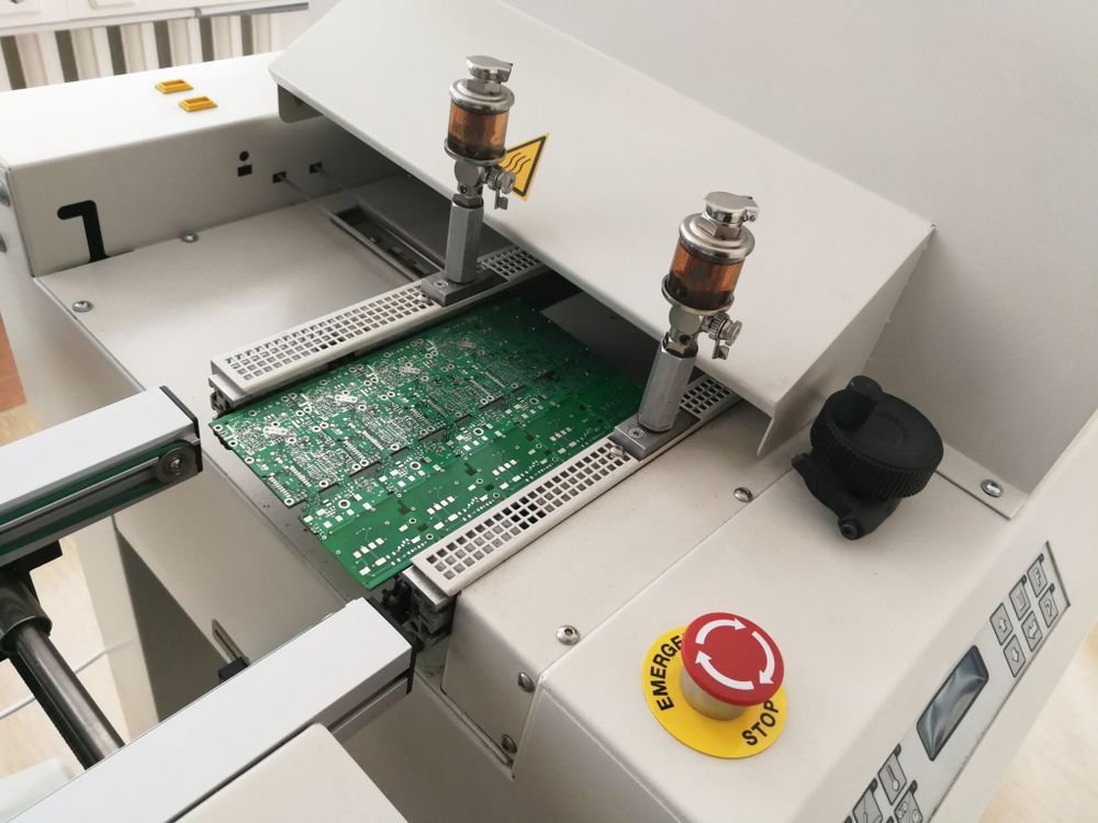 Circuit board in industrial machine with red emergency stop button and metal clamps
