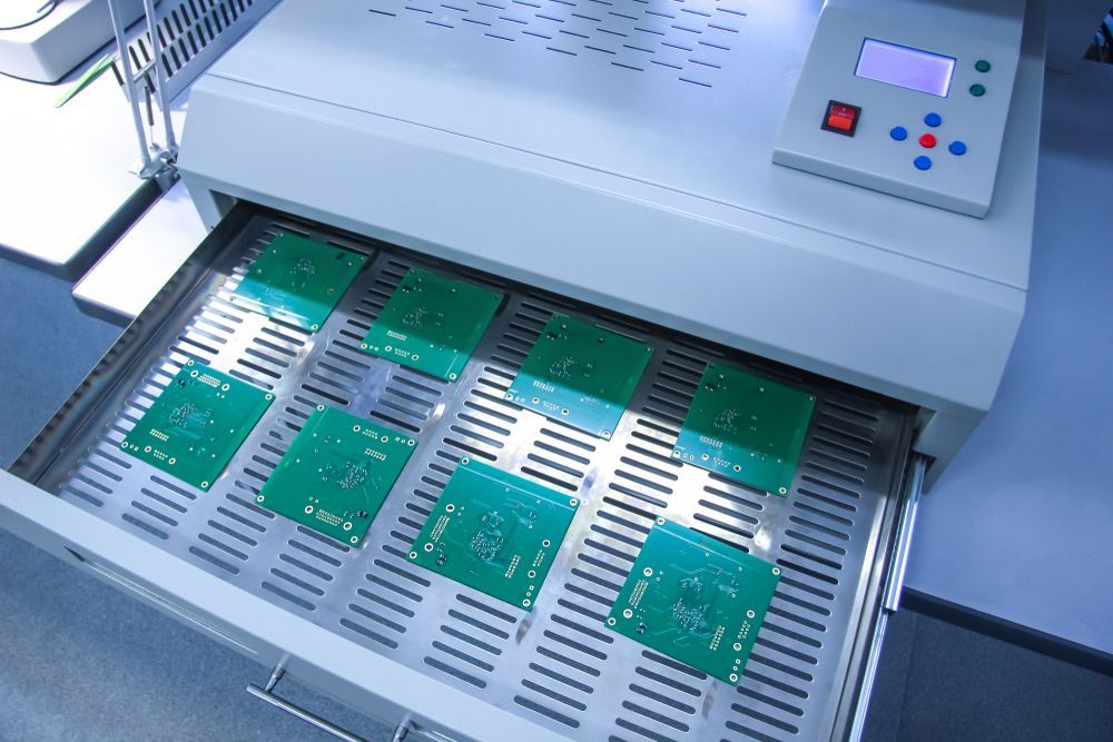 Circuit board assembly machine handling green PCBs on a conveyor belt