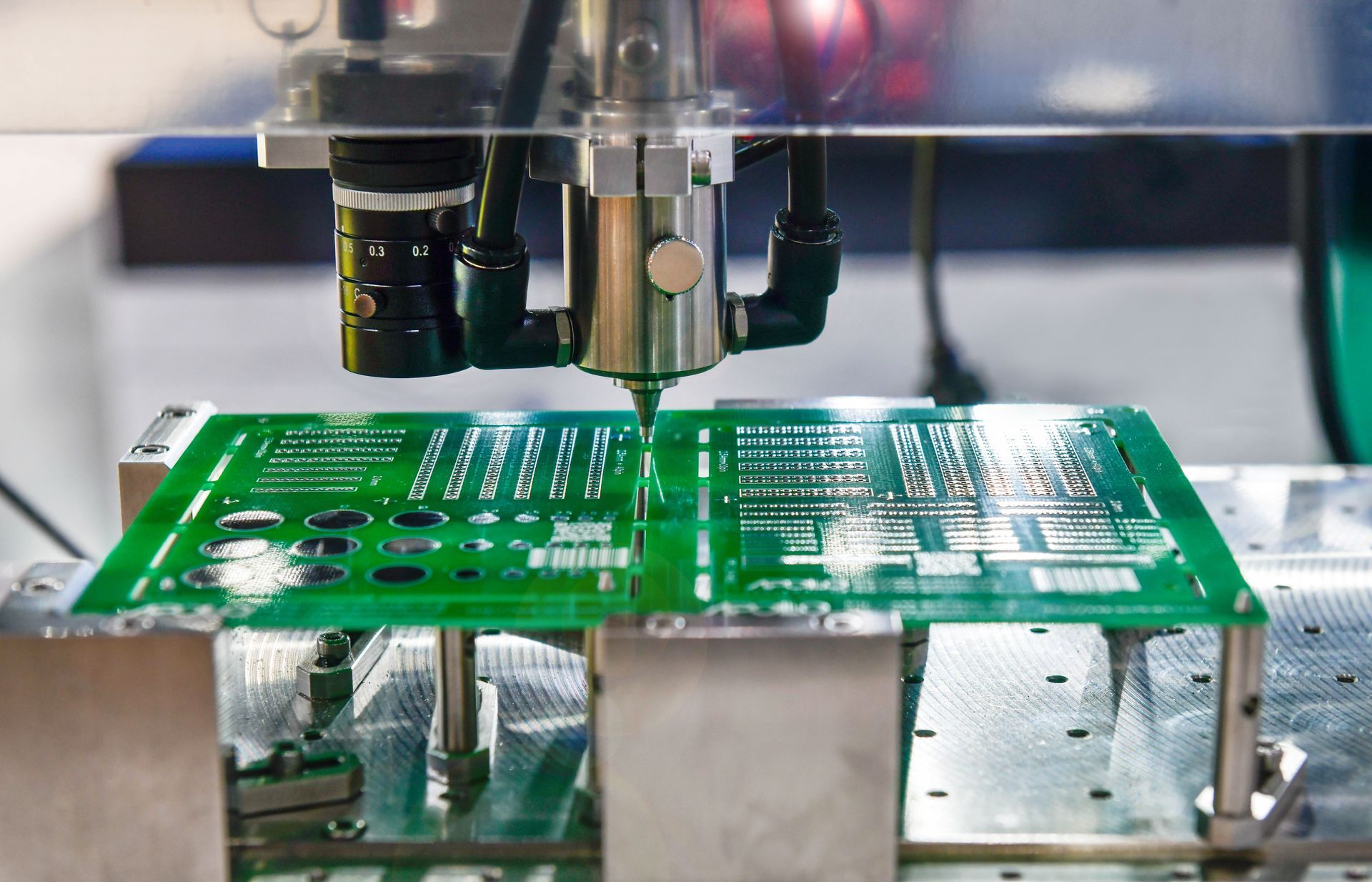 Automated machine applying solder to a green circuit board in a factory setting.