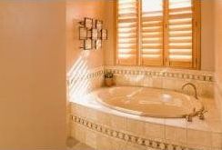 A bathroom with a jacuzzi tub and shutters on the windows.