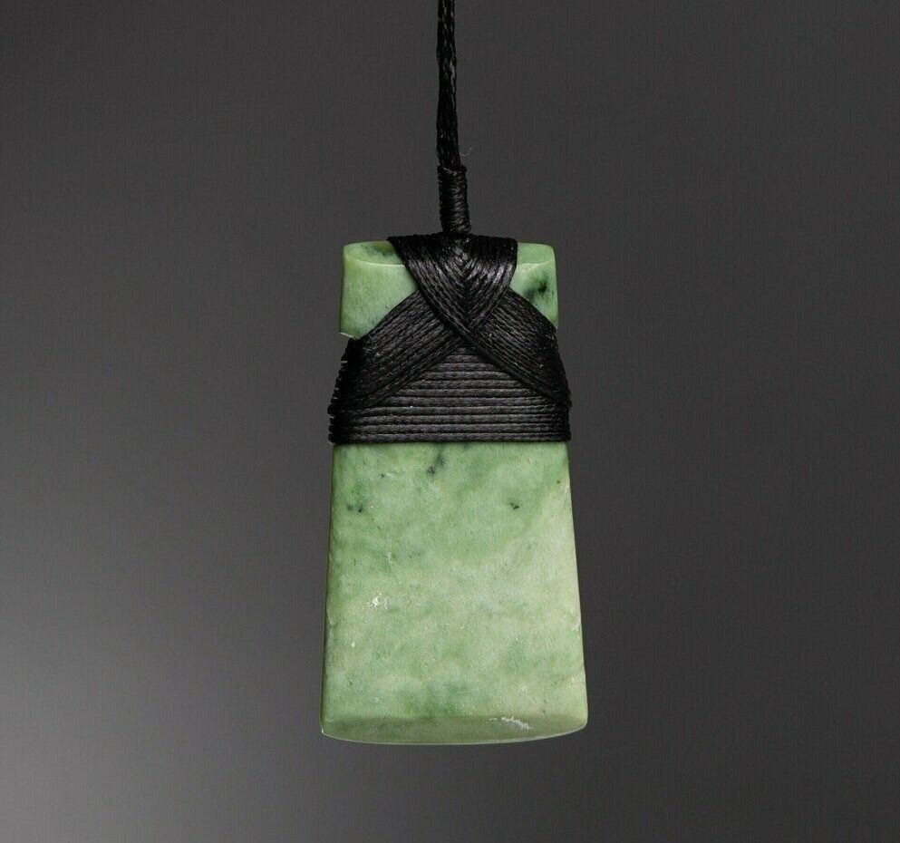 A green pendant is hanging from a black string.