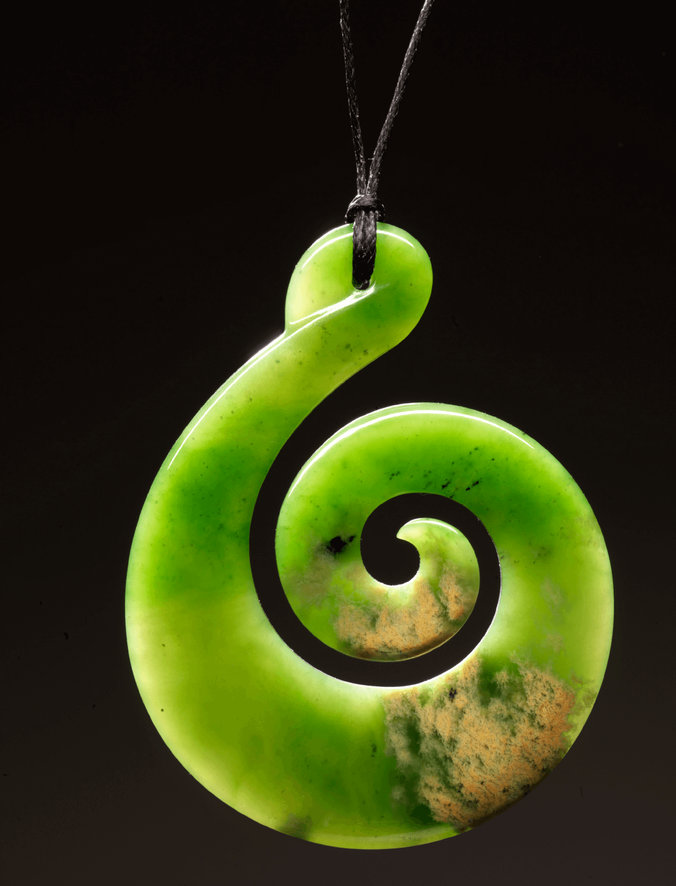 A green pendant with a black spiral on it