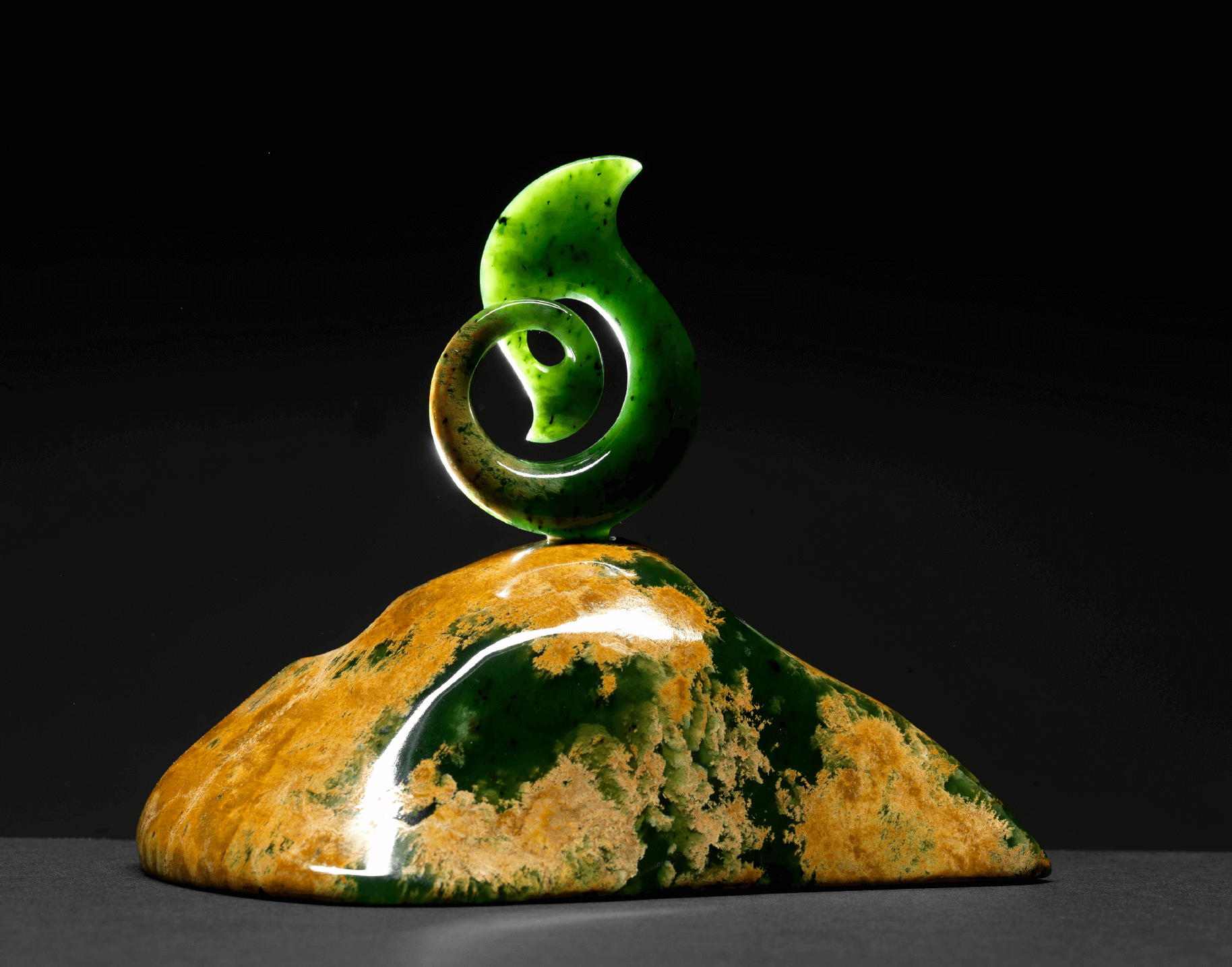 A sculpture of a green swirl on top of a rock