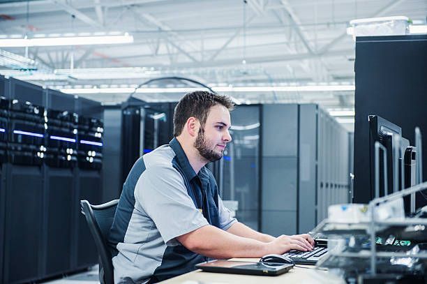 IT Network Support technician working on computer in server room.