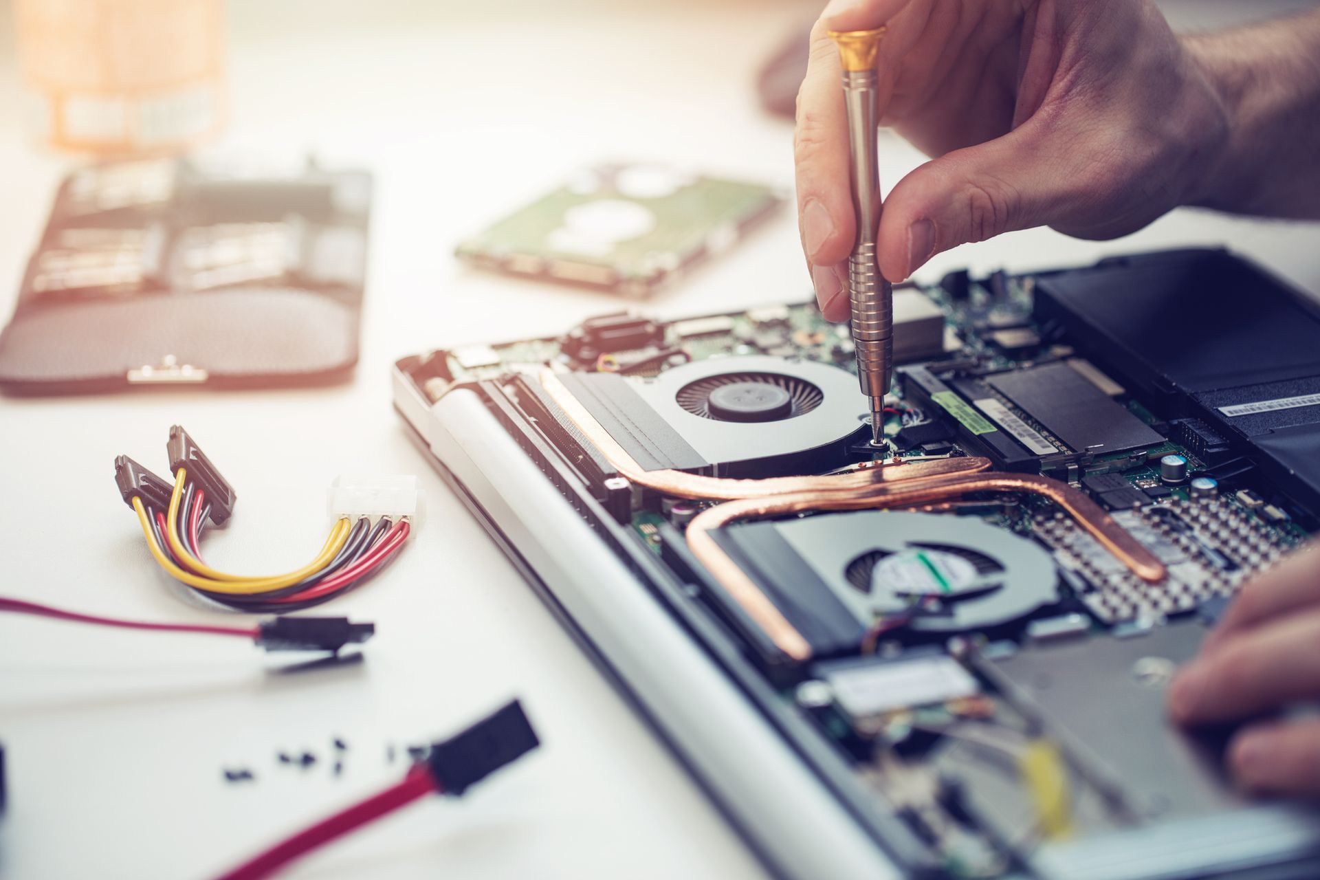 Close-up of a technician's hands performing computer repair services on a laptop.