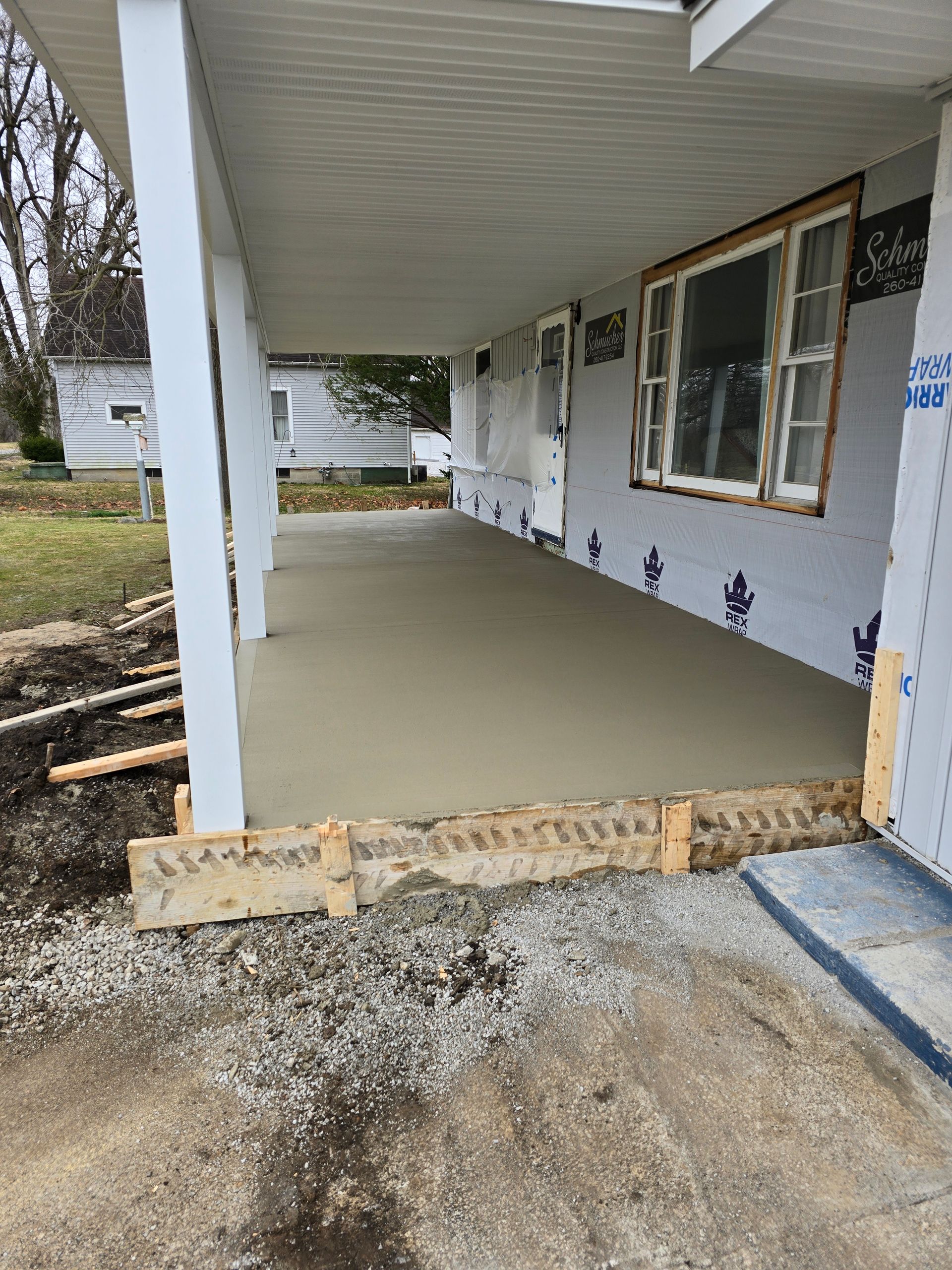 A concrete porch is being built on the side of a house.