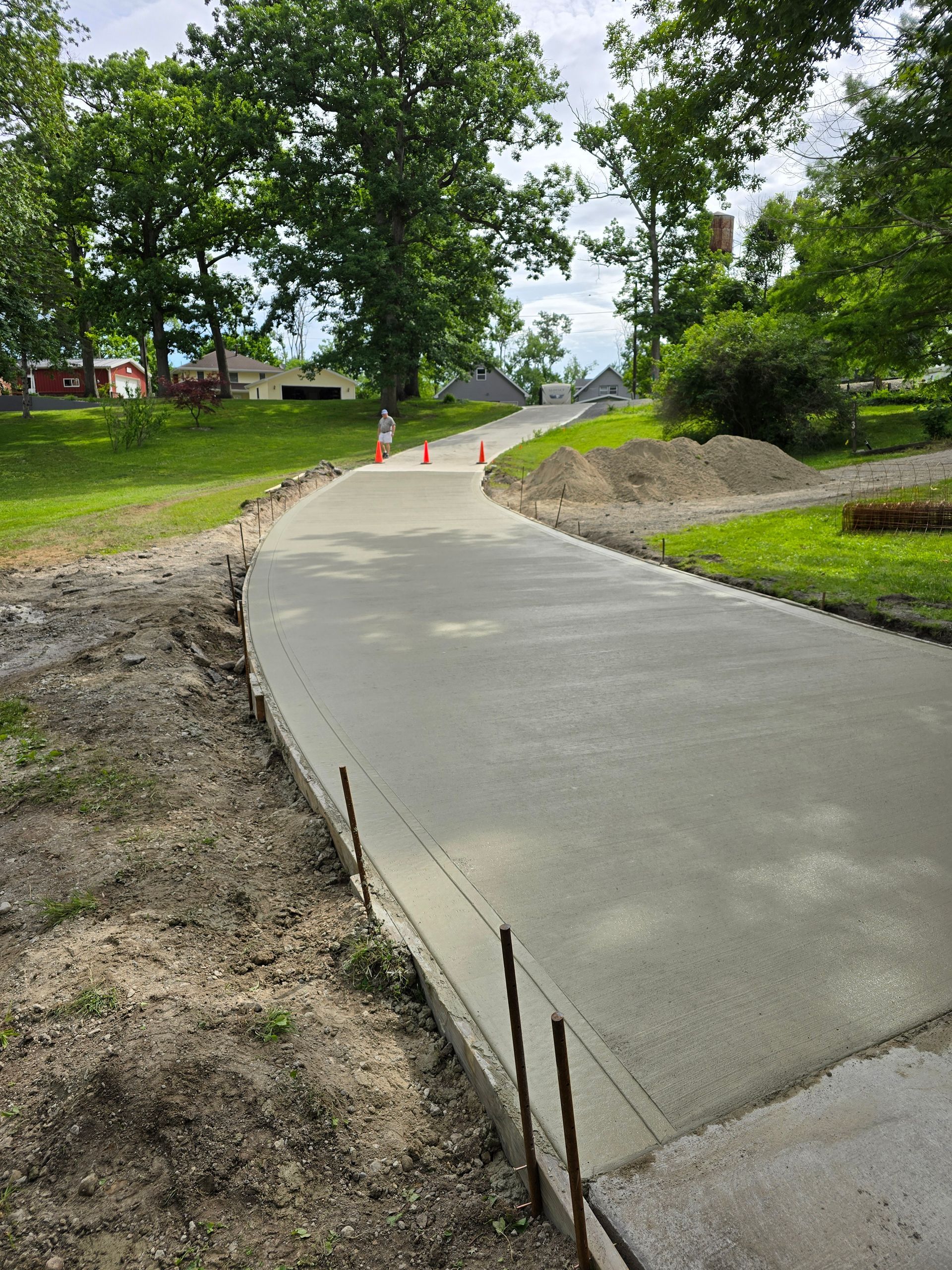 A concrete driveway is being built next to a grassy hill.
