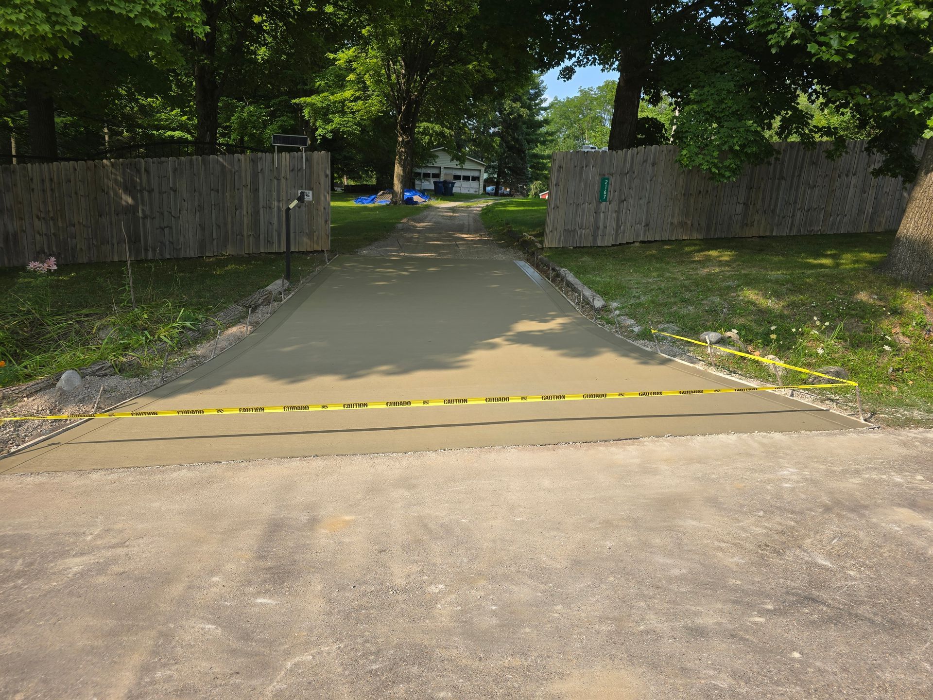 A concrete driveway with a fence and trees in the background