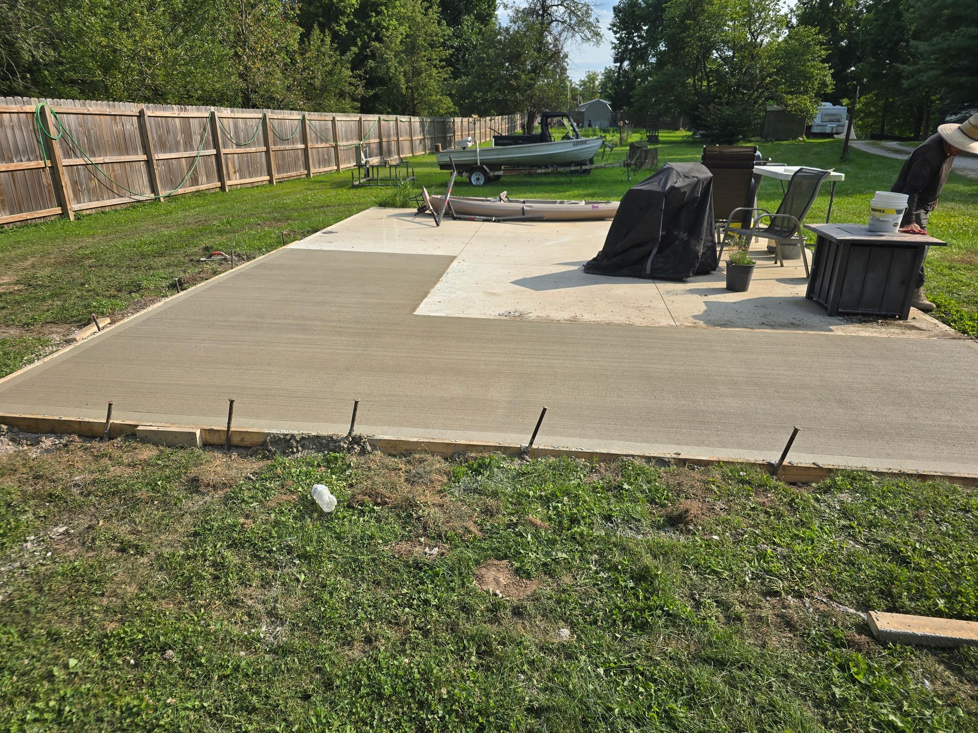 A concrete patio is being built in a backyard.