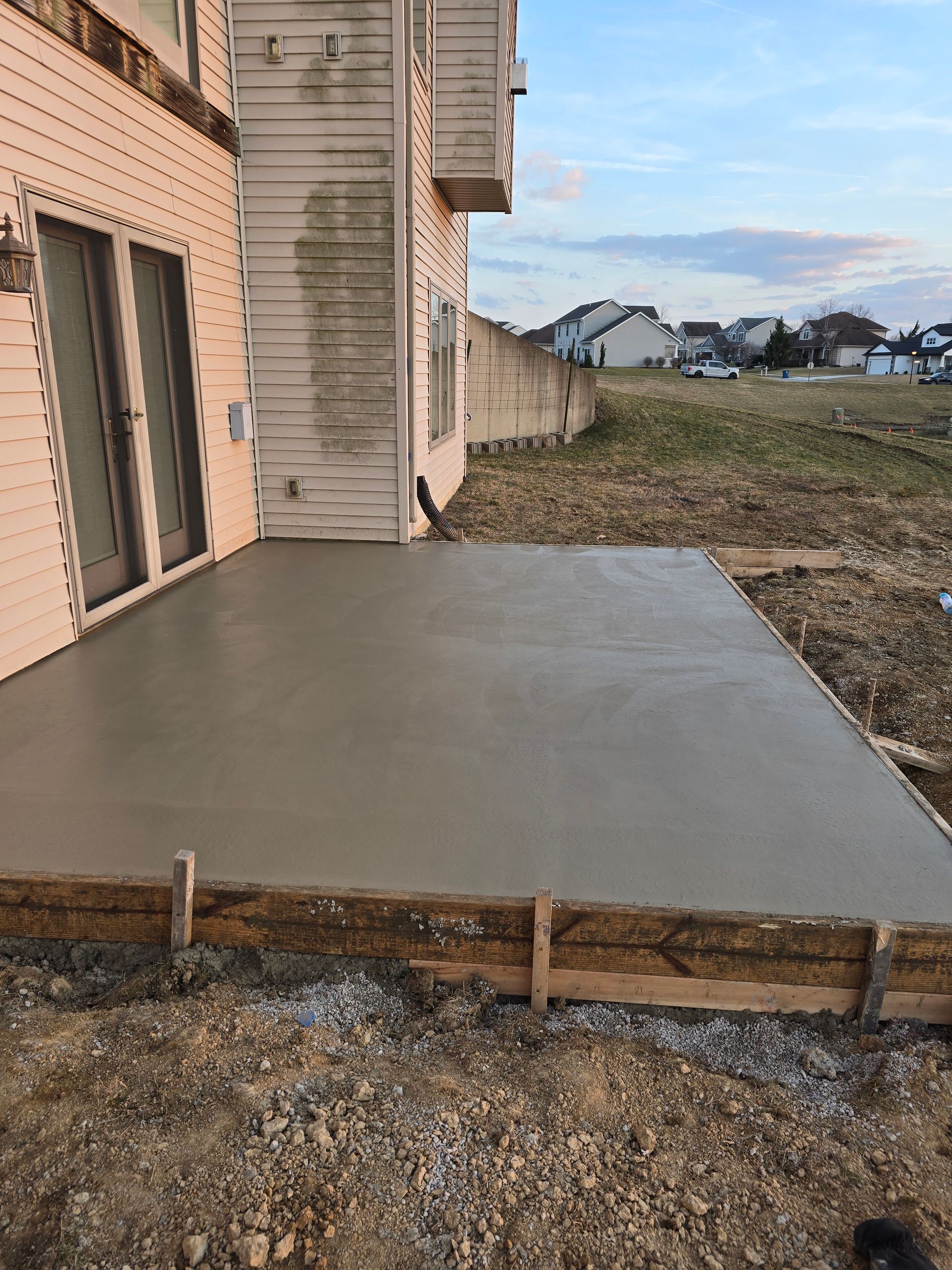 A concrete patio is being built in front of a house.