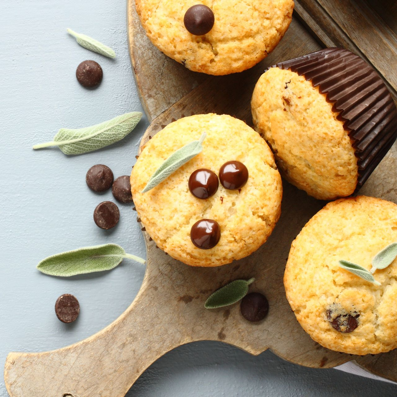 Muffin con gocce di cioccolato e salvia su un tagliere di legno.